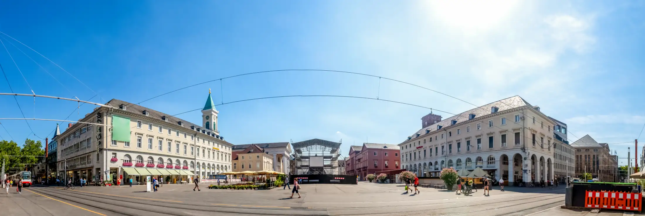 Panorama vom Pyramidenmarkt Karlsruhe: links die Immobilien östliche Kaiserstraße und Marktplatz, daneben die Stadtkirche, mittig verdeckt sind Pyramide und südlich davon Ludwigsbrunnen, daneben Rathaus, rechts Immobilien westliche Kaiserstraße und Markt.
