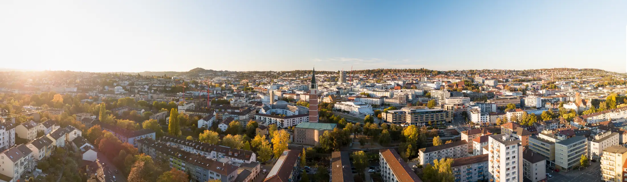 Luftaufnahme Pforzheim: links Immobilien westliches Pforzheim, mittig Stadtkirche Uhrturm daneben Lindenplatz zwischen Enz und Nagold, rechts dahinter Sparkassenturm südwestlich des Hauptbahnhofes, rechts Immobilien östliches Pforzheim
