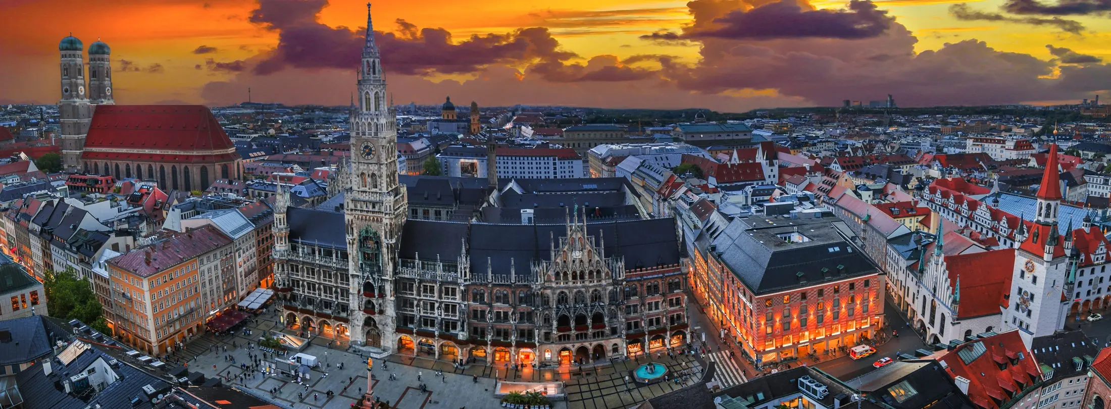 Luftbild von der Altstadt München in der Dämmerung mit seinen bekannten Wahrzeichen bzw. Immobilien, links die Frauenkirche, in der Mitte das neue Rathaus und der Marienplatz.