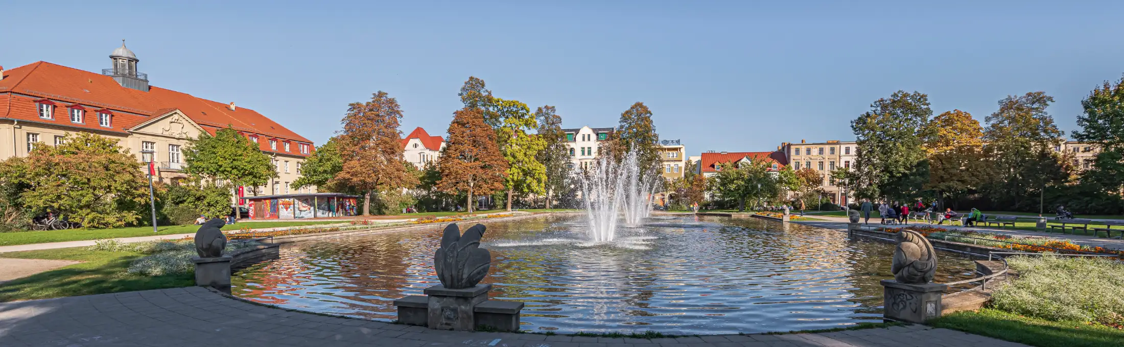 Der Schillerpark / Schillerplatz in Cottbus, links Immobilien August-Bebel-Straße., mittig der Brunnen im Schillerpark mit seinen 3 Fontänen, dahinter Immobilien Wernerstraße, rechts südlicher Teil Schillerplatz