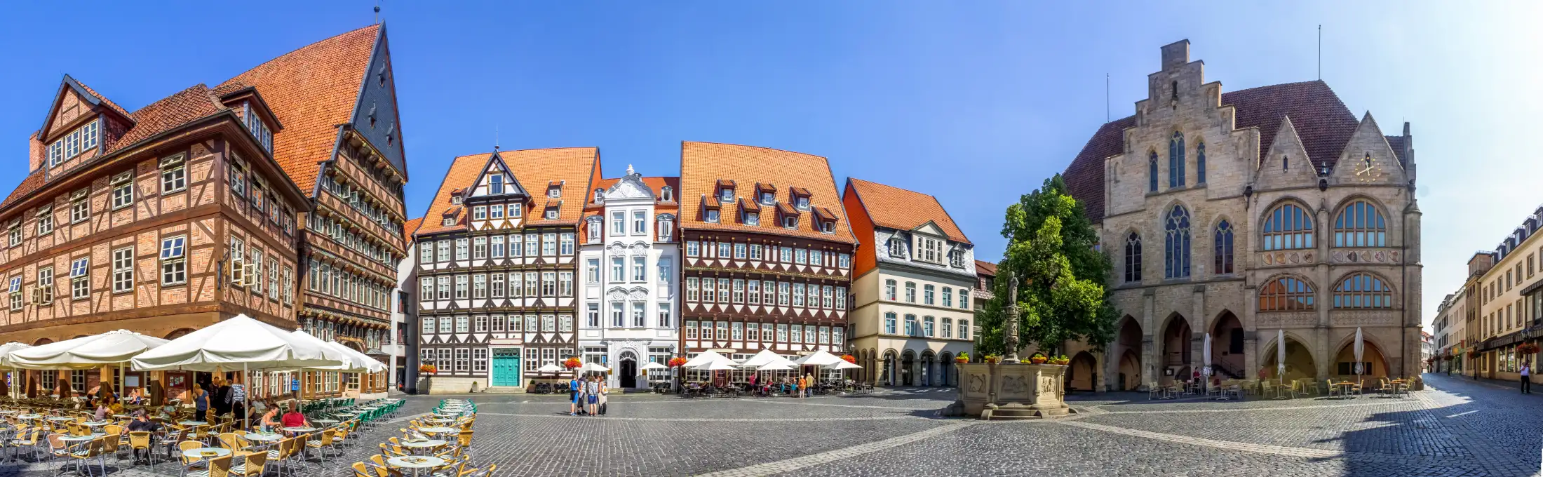 Panoramaaufnahme Marktplatz Hildesheim: links Bäckeramtshaus und Knochenhaueramtshaus, mittig Immobilien nördlicher Markt / Marktstraße mit Einwohnermeldeamt, davor Rolandbrunnen, rechts Rathaus Hildesheim, ganz rechts Immobilien Rathausstraße