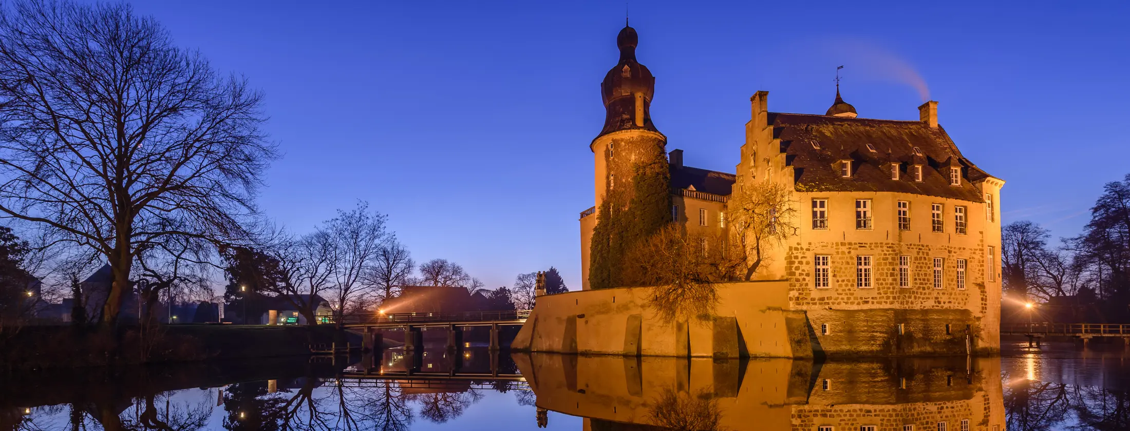 Bild der angeleuchteten Wasserburg Gemen bzw. von Schloss Gemen in Borken in der Dämmerung, Ansicht von Osten