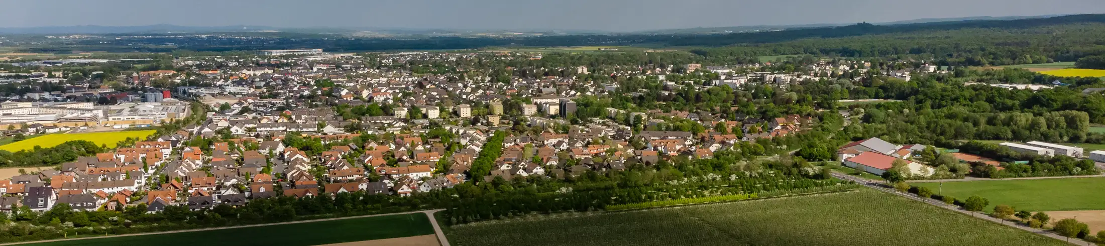 Luftaufnahme von Rheinbach von Westen: im Vordergrund die Landesstraße L 493, dahinter links und mittig Immobilien westliche Kernstadt Rheinbach, rechts „Robinson Rheinbach“ und weitere Immobilien Schornbuschweg