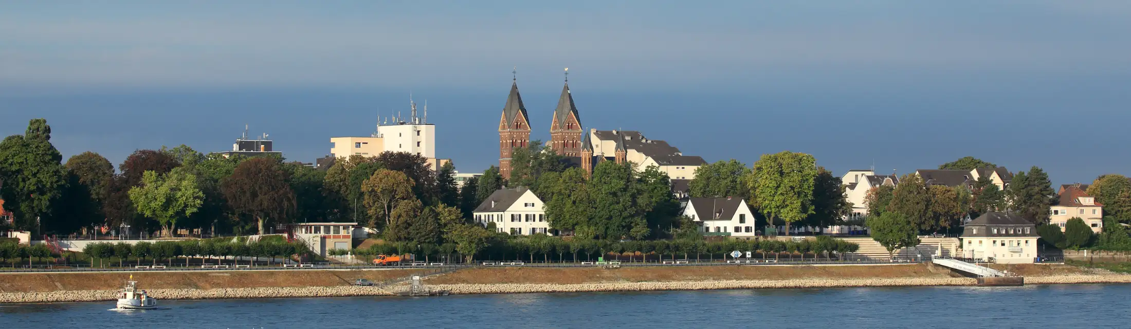 Wesseling: im Vordergrund der Rhein, dahinter links Immobilien Bonner Straße, mittig die Kirche St. Germanus, rechts Immobilien Kölner Straße / Uferstraße