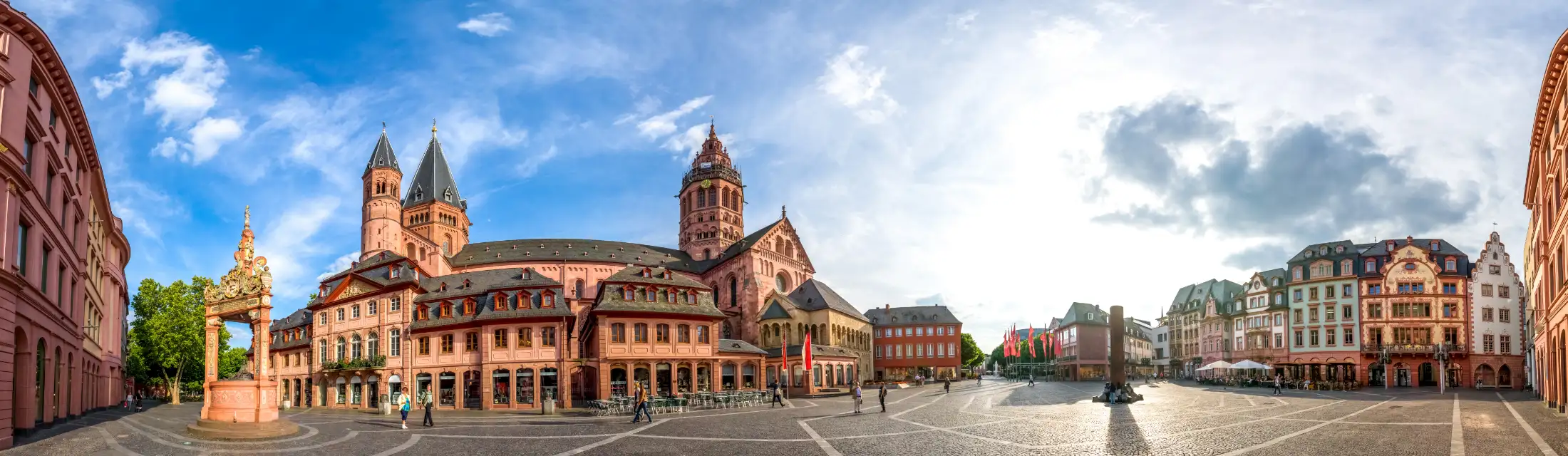 Panoramaaufnahme Mainz Marktplatz: links Immobilien östlicher Markt, historischer Renaissance-Marktbrunnen, daneben Dom St. Martin zu Mainz, rechts Heunensäule, daneben Immobilien westlicher Markt/Schusterstraße, ganz rechts Immobilien nördlicher Markt