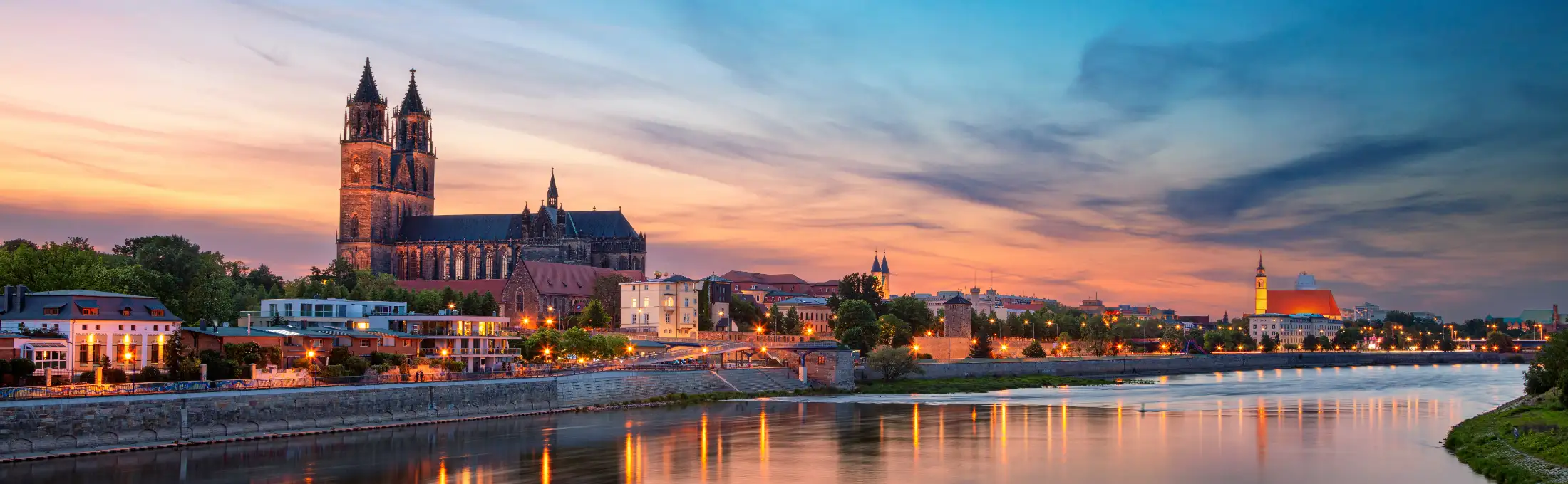 Panoramaaufnahme von Magdeburg: vorne die Elbe, links Dom zu Magdeburg, Immobilien Altstadt und Schleinufer, mittig alte Stadtmauer mit Fürstenwall und Wehrturm Kiek in de Köken, dahinter Kunstmuseum - Kloster Unser Lieben Frauen, rechts Johanniskirche.