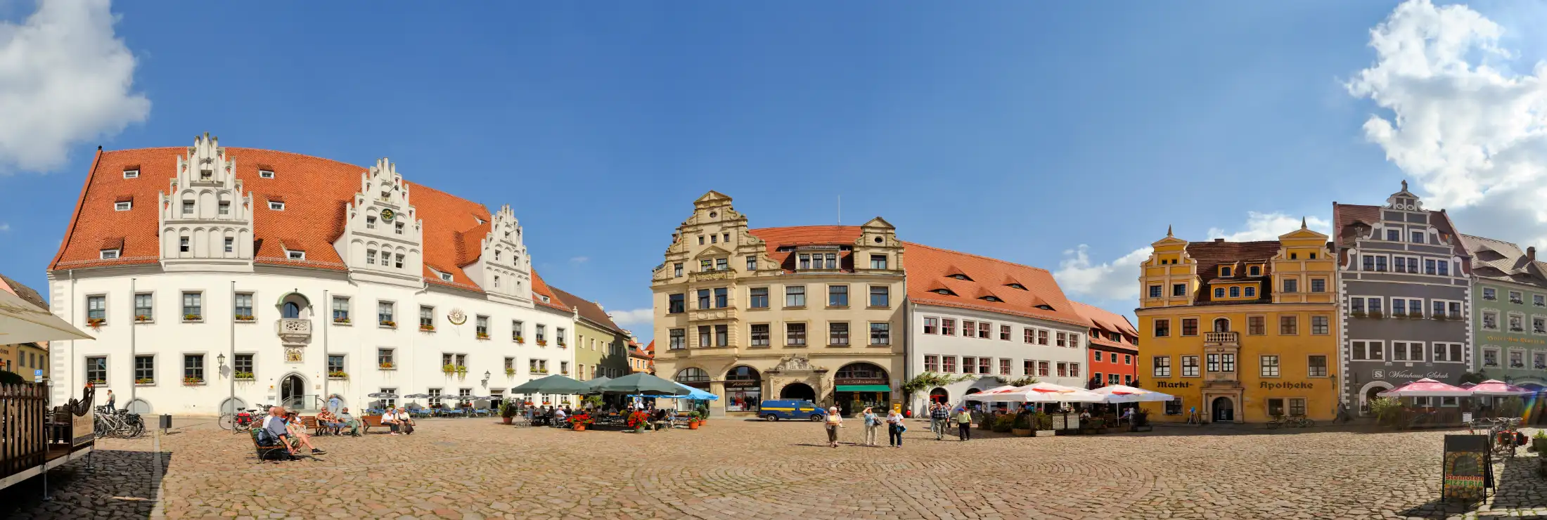Panoramaaufnahme Marktplatz Meißen: links das Rathaus Meißen (mit Sonnenuhr an der Fassade) und Elbstraße, daneben die östlichen Immobilien am Markt u. a. die Tourist Information und Marktgasse, rechts die südlichen Immobilien am Markt